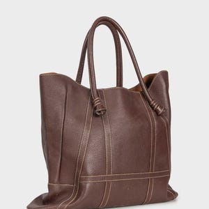 May include: A brown leather tote bag with knotted handles and stitched details.