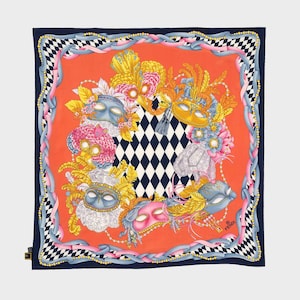 May include: A square silk scarf with a carnival mask design. The scarf features a central orange panel with masks, flowers, and feathers. It has a navy blue border with a checkered pattern. The masks are in blue, pink, and gold.