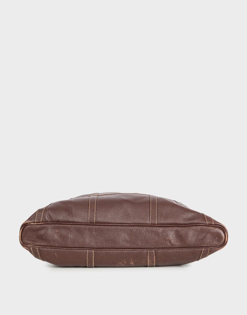 May include: A brown leather tote bag with a stitched design. The bag is shown from the bottom.