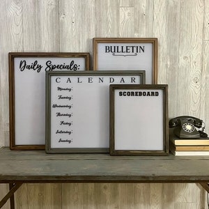 May include: Four framed whiteboards with black text. The top board says "BULLETIN" with a decorative flourish. The next board says "CALENDAR" and lists the days of the week. The third board says "SCOREBOARD". The bottom board says "Daily Specials:"