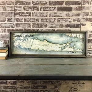 May include: A framed vintage map of Long Island, New York, with the title "Long Island" and the date "Circa 1819". The map is printed on paper with a light blue background and brown lines representing roads and waterways.