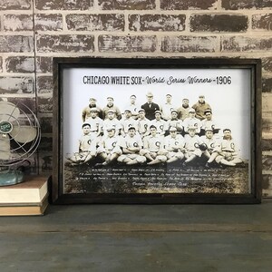 May include: A framed black and white photo of the 1906 Chicago White Sox World Series winning team. The photo shows the players in their uniforms, sitting in a row. The text "CHICAGO WHITE SOX - World Series Winners - 1906" is printed at the top of the photo.
