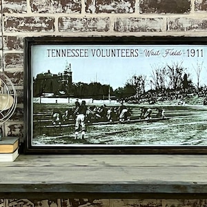 May include: A framed black and white photo of a football game. The photo is titled "Tennessee Volunteers - Wait Field - 1911".