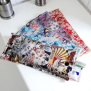 Peut inclure: Plusieurs pochettes en tissu colorées avec des motifs japonais, notamment floraux et manga. Un tube de dentifrice et une brosse à dents sont visibles. Ces pochettes sont probablement destinées au voyage ou au rangement.