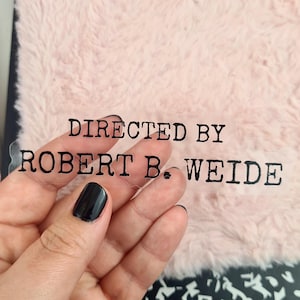 May include: A clear sticker with black text that reads "DIRECTED BY ROBERT B. WEIDE"