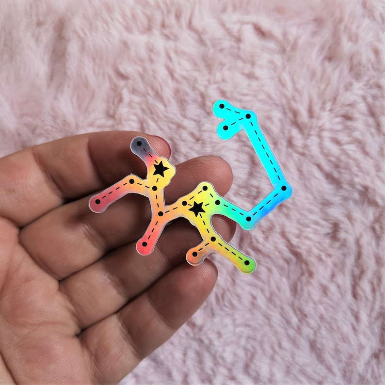 May include: A holographic sticker of the Sagittarius constellation with black stars and a rainbow gradient.