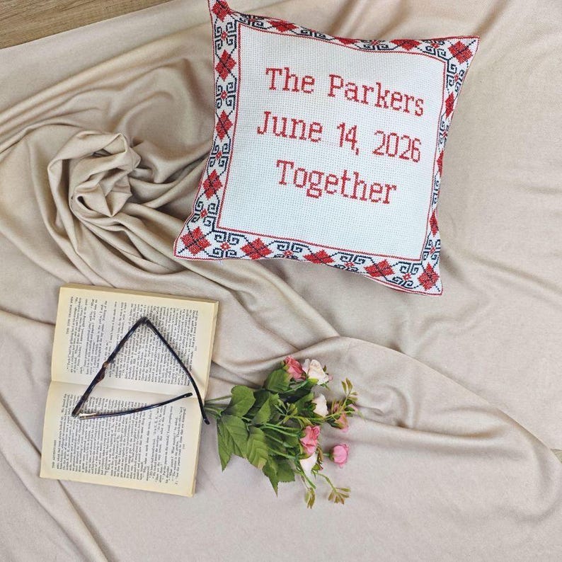 Lifestyle image of the square coral gray personalized decorative pillow styled on a rustic armchair with a cozy throw blanket and books.
