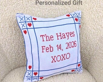 May include: White square pillow with blue border and red heart and XOXO details. The text "The Hayes Feb 14, 2026 XOXO" is embroidered in red. The pillow is a personalized gift.