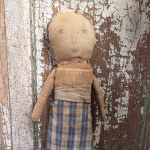 May include: A handmade rag doll with a brown and blue plaid skirt. The doll has a simple face and is made from fabric scraps.