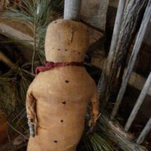 May include: A handmade primitive style rag doll with a brown fabric body, black button eyes, and a red fabric scarf. The doll is sitting on a wooden chair.
