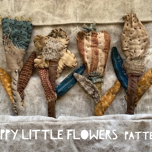 May include: Five handmade fabric flowers in various colors and patterns, including blue, brown, red, and white, with the text "HAPPY LITTLE FLOWERS PATTERN" at the bottom of the image.