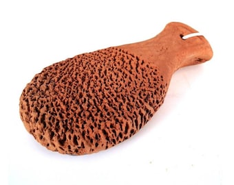 Op de afbeelding: Een terracotta voet scrub in de vorm van een vis. De scrub heeft een ruw, getextureerd oppervlak en een glad handvat.