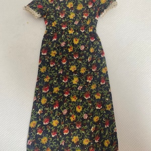 May include: A vintage-style dress with a dark background and a floral pattern in yellow, red, and white. The dress has short sleeves with lace trim and a fitted waist. The hemline is slightly frayed.