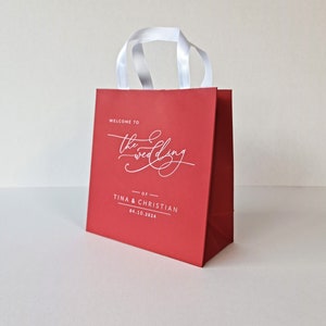 Sacchetti di benvenuto per matrimonio in carta rossa e stampa bianca. Completamente personalizzabili. Manici in raso. Sacchetti regalo. Sacchetti per hotel per gli ospiti. Sacchetti di carta. Bomboniere.