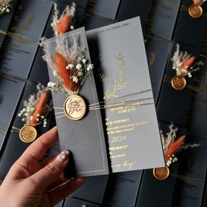 Inviti di nozze in acrilico con fiori secchi e sigillo di ceralacca in copertina nera. Stampa in lamina d'oro. Design completamente personalizzato. Acrilico morbido satinato.