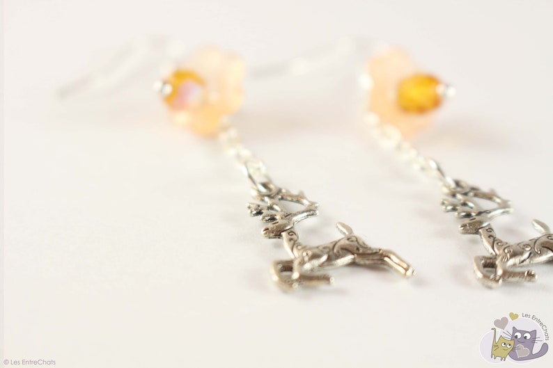 Dangling earrings with silvery metal deer and flower in resin