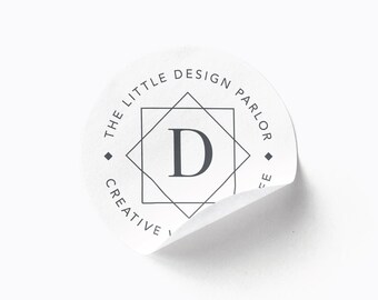May include: A white round sticker with a black and white geometric design. The text "The Little Design Parlor Creative" is written around the outside of the design. The letter "D" is in the center of the design.