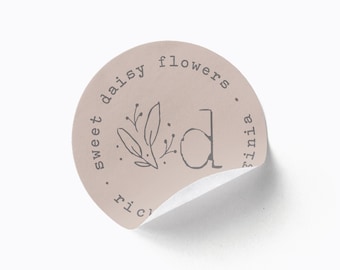 May include: A round, light pink sticker with the text "sweet daisy flowers" and "richmond virginia" in a circular arrangement. A stylized floral design and the letter "d" are in the center. The sticker's edge is partially peeled back.