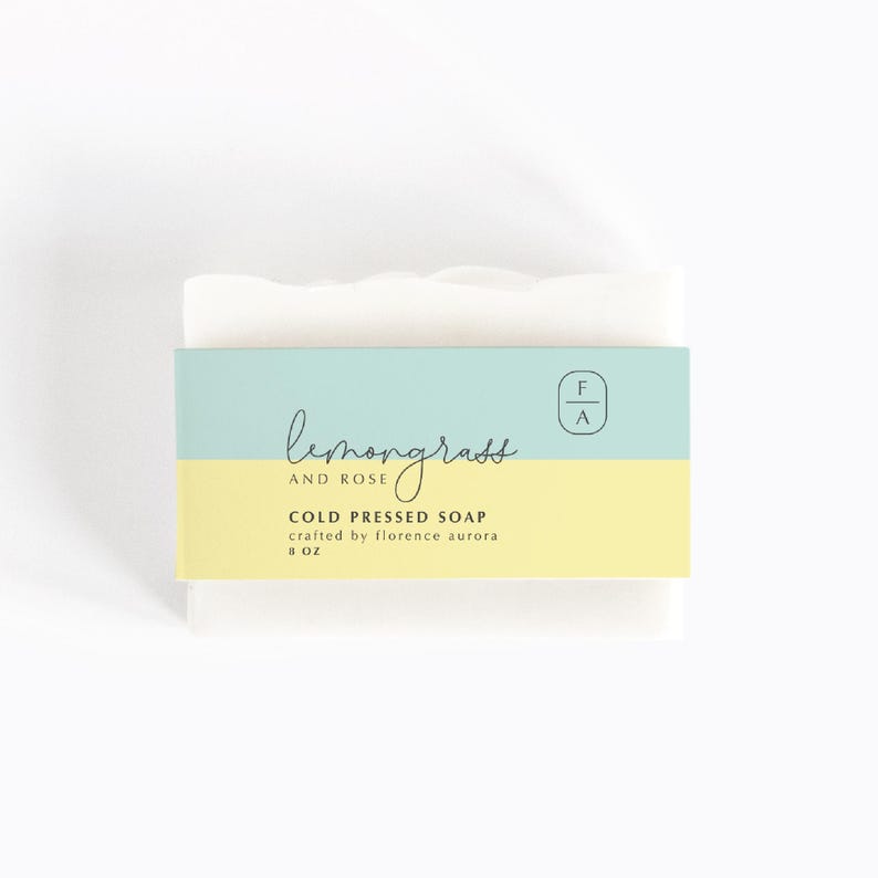 K&ouml;nnte beinhalten: Eine wei&szlig;e Seifenstange mit einem hellblauen und gelben Etikett, auf dem "Lemongrass and Rose Cold Pressed Soap crafted by Florence Aurora 8 oz" und ein kleines Logo mit der Aufschrift "F A" steht.