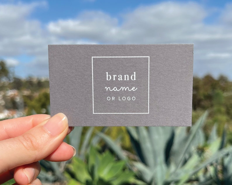 May include: A gray business card with a white border around the text "brand name or logo".
