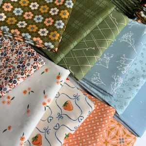 May include: A collection of folded fabric squares featuring diverse patterns including a mustard yellow honeycomb floral print, green plaid, blue botanical sketches, white with orange flowers, cream with strawberries, and orange geometric designs.