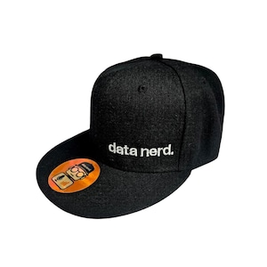 May include: Black flat-peak cap with the white embroidered text "data nerd." A small, circular sticker with a cartoon image is on the brim. The cap is made of a textured fabric.