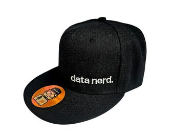May include: Black flat-brimmed baseball cap with the embroidered text "data nerd." A small, round sticker with a cartoon image is on the brim. The cap is made of a textured fabric.