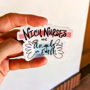 May include: White sticker with black text that reads "NICU NURSES are angels on Earth". The sticker has a pink and blue stripe across the top and a halo above the word "angels".