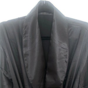 May include: A black satin robe with a shawl collar. The robe is made of a soft, luxurious fabric and has a relaxed fit.