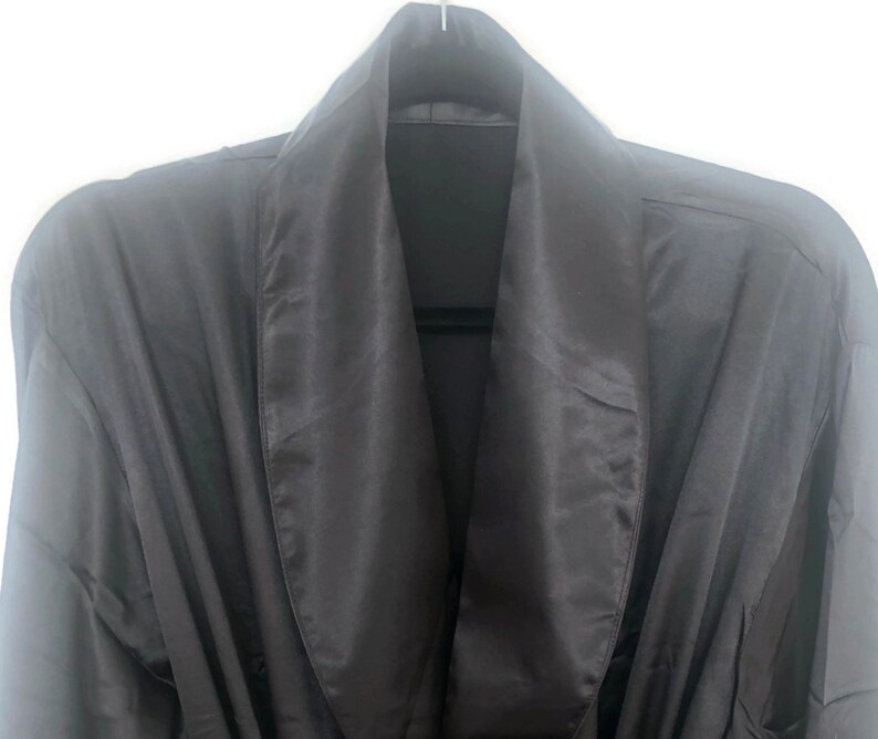May include: A black satin robe with a shawl collar. The robe is made of a soft, luxurious fabric and has a relaxed fit.
