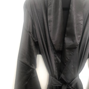 May include: A black satin robe with a shawl collar and a tie belt.