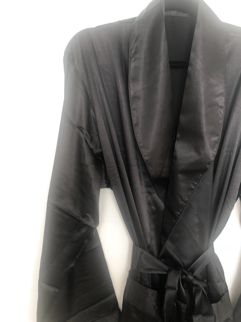 May include: A black satin robe with a shawl collar and a tie belt.
