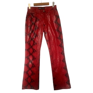 May include: Red faux leather trousers with a black snakeskin pattern. The trousers are hanging on a wooden hanger. The trousers have a classic five-pocket design and a straight leg cut.