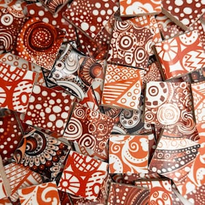 May include: A collection of square ceramic tiles in shades of brown, white, and orange. Each tile features unique patterns, including dots, swirls, and geometric shapes. The tiles are arranged in a random, overlapping manner, creating a mosaic effect.