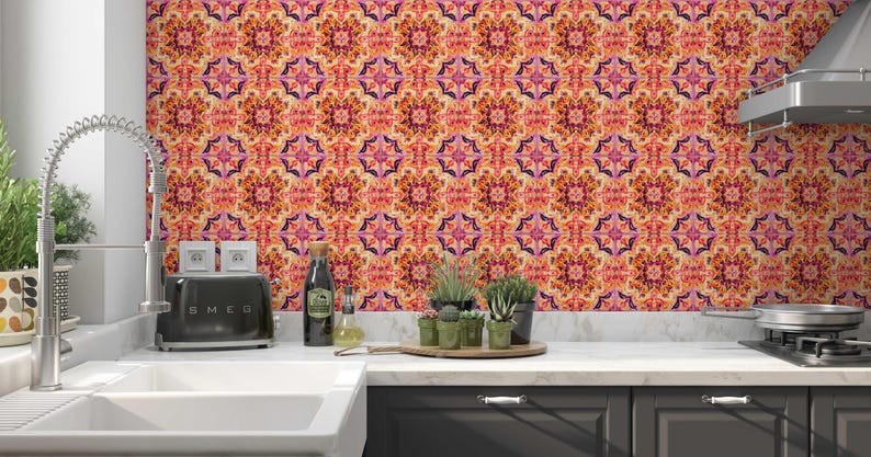 May include: A kitchen with a patterned orange, pink, and purple backsplash. A black toaster, sink, and a wooden tray with small potted plants sit on the countertop. A stainless steel tap and extractor fan are also visible.