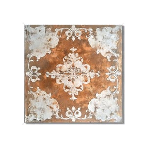 May include: Square decorative wall art with a distressed copper-colored background and a white, ornate, scrollwork design. The design features a central medallion and corner accents, creating a vintage aesthetic.
