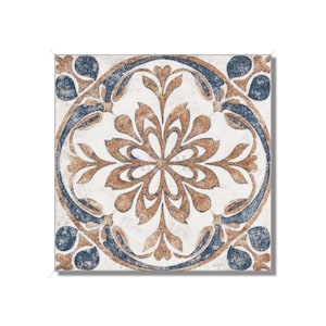May include: A square ceramic tile with a white background and a blue and brown floral pattern. The pattern is a stylized flower with a circular design.