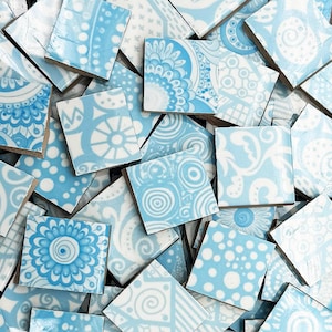 May include: A collection of square ceramic tiles with various blue and white patterns. The designs include floral, dotted, and swirling motifs. The tiles are scattered, showcasing the different patterns and textures.
