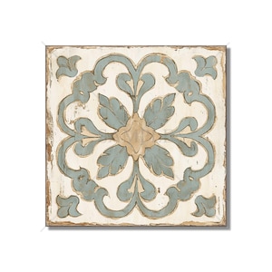 May include: Square, distressed wooden tile with a central floral design. The design features a light blue and beige floral pattern on a cream-colored background. The edges of the tile are brown.