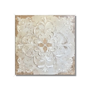 May include: Square, off-white wall art with a raised, ornate floral design. The design features a central flower and symmetrical, swirling leaves in white against a textured, light beige background. The edges have a distressed, aged appearance.