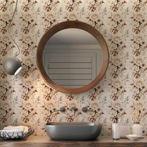 Puede incluir: Un tocador de ba&ntilde;o con un espejo redondo de madera, un lavabo de porcelana blanca y una encimera de madera marr&oacute;n. Las paredes est&aacute;n alicatadas con un patr&oacute;n floral en tonos marrones y blancos.