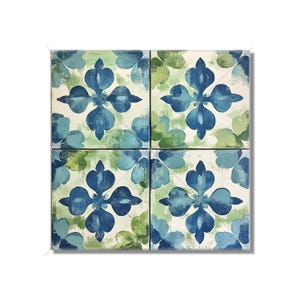 May include: Four square ceramic tiles with a floral design. Each tile features a central blue flower with four petals, surrounded by blue and green accents on a white background. The tiles are arranged in a 2x2 grid.
