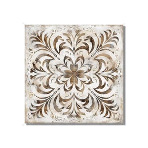 May include: A square, white canvas with a brown and white intricate floral pattern. The pattern is symmetrical and has a vintage, distressed look.