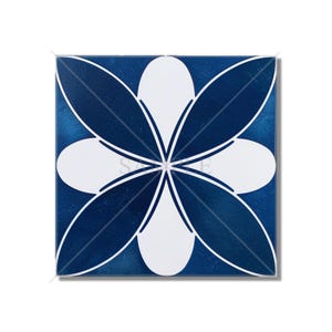 May include: A blue and white ceramic tile with a floral design. The tile features a white flower with eight petals, each petal has a blue outline. The background of the tile is a deep blue color.