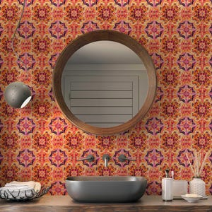 May include: A bathroom with a round wooden mirror, a dark grey oval sink, and wallpaper with a repeating floral pattern in orange, pink, and purple. A grey light fixture hangs from the ceiling. The wallpaper is the focal point.