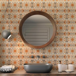 May include: A bathroom vanity with a round wooden mirror, a gray ceramic sink, and a patterned wallpaper with orange and brown tones. The vanity has a wooden countertop and a chrome faucet.