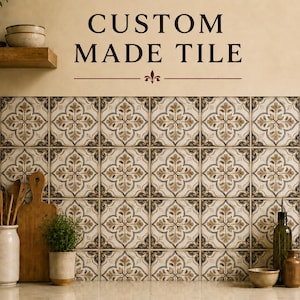 May include: A wall backsplash featuring square tiles with a repeating brown, beige, and black floral pattern. The text CUSTOM MADE TILE is printed above the tiles. The kitchen counter below holds a wooden cutting board, a potted plant, and bottles.