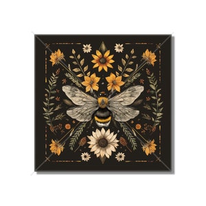May include: A black background with a symmetrical design of yellow and orange flowers, leaves, and a bumblebee in the center.