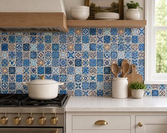 May include: A kitchen backsplash featuring a grid of square tiles in various blue, white, and tan patterns. A white lidded pot sits on a stainless steel stove, while a white ceramic crock holds wooden spoons next to a small potted green plant.
