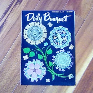 May include: A vintage crochet pattern book cover featuring a blue background with a white title "Doily Bouquet" and four white crocheted doilies with butterflies and green leaves.